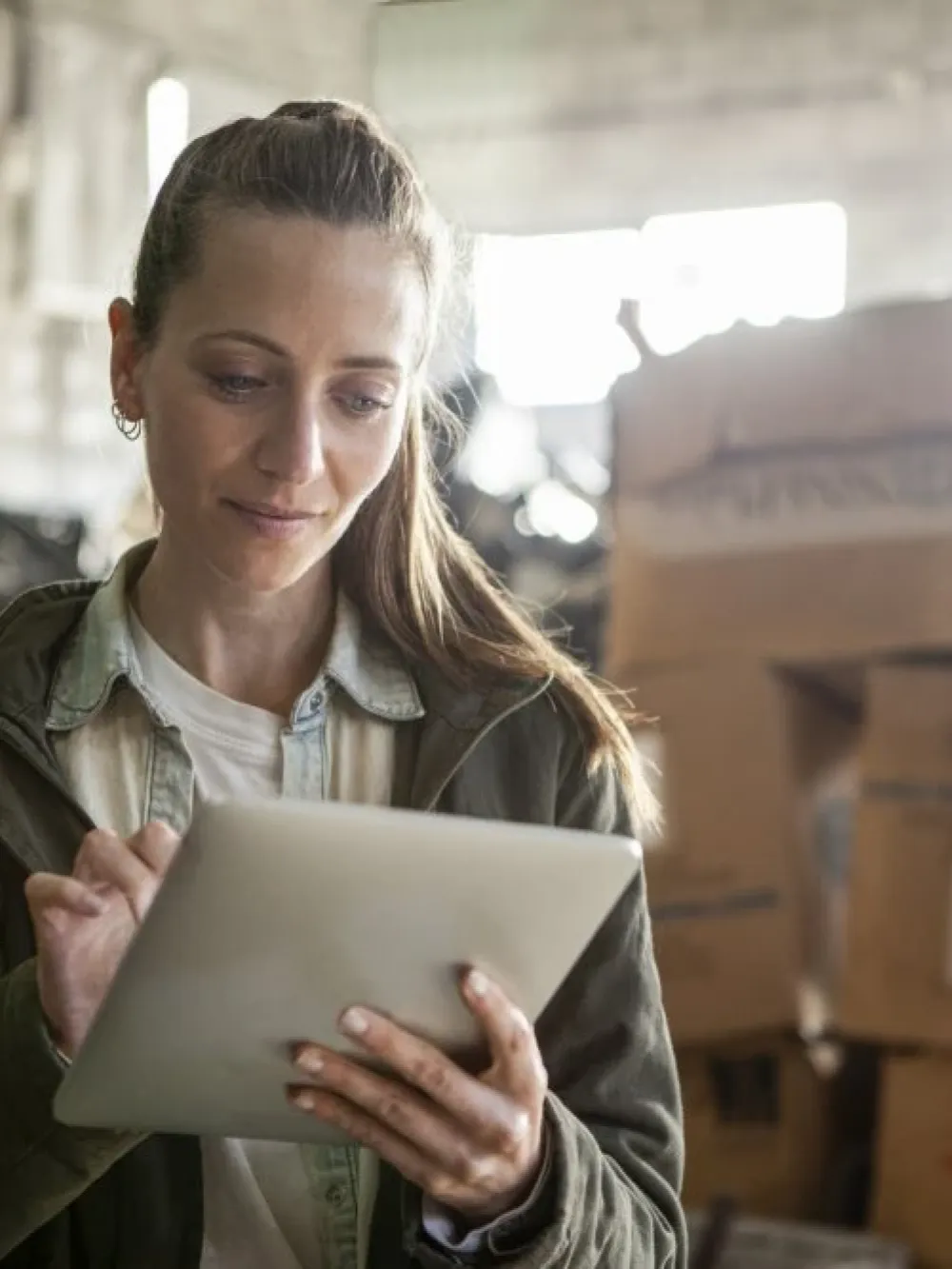 Personne utilisant une tablette dans un entrepôt rempli de boîtes en carton.