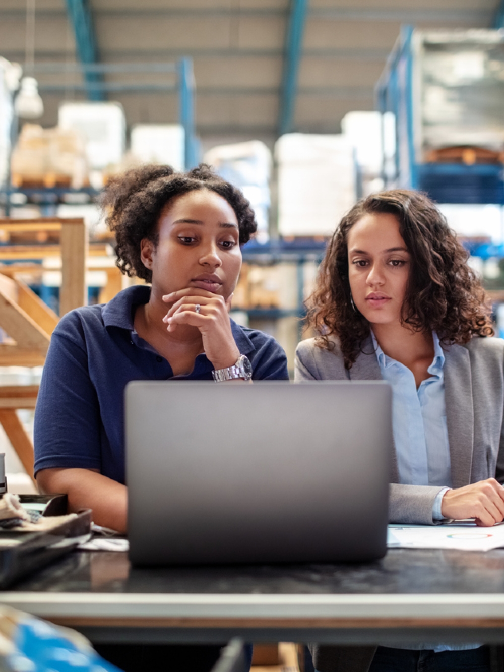 Deux femmes dans un entrepôt se questionnant devant un ordinateur
